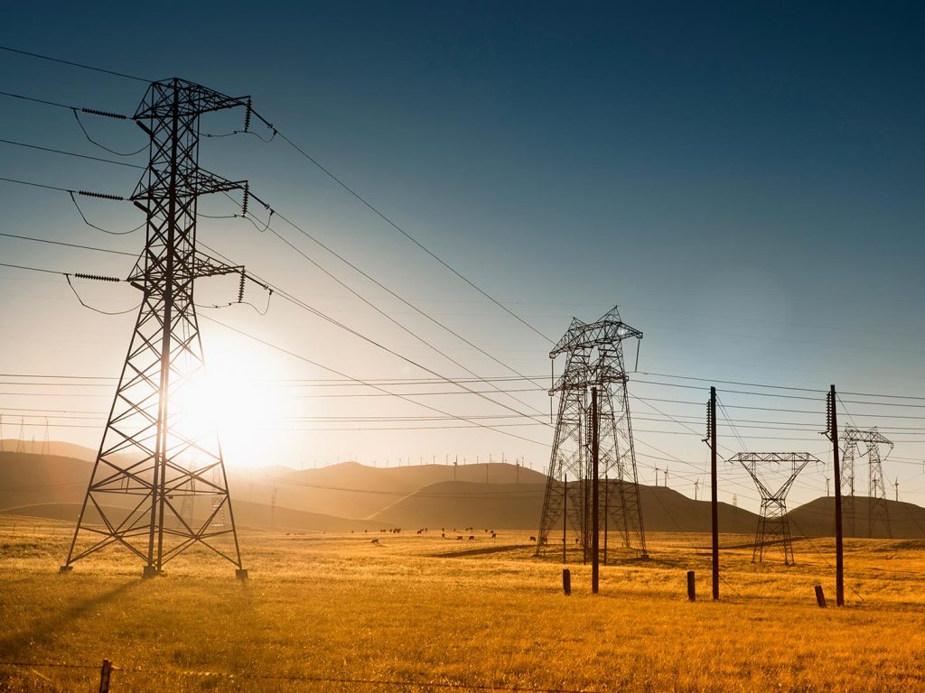 Power lines above dry grass with sun shining